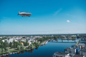 hydrogen fuel cell blimp flying over a river in a city