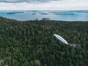 hydrogen fuel cell powered blimp flying over a thick forest